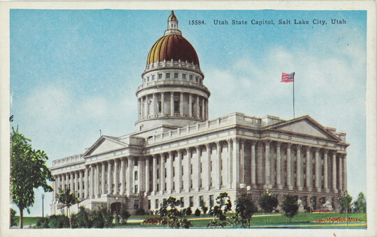 A color postcard of a gold domed government building with many columns.