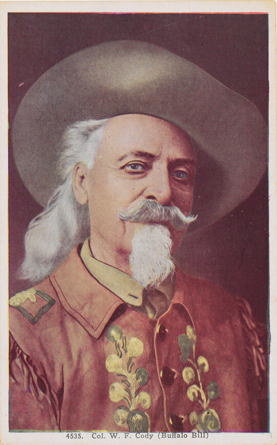 A color photograph postcard of a portrait of a White man wearing a cowboy hat, long gray hair, moustache and goatee, and a decorative jacket.