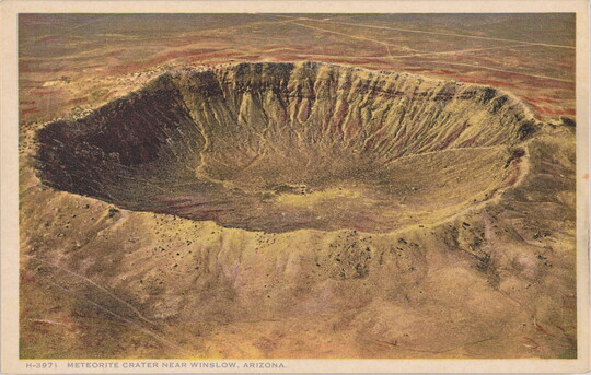 A color postcard of a bird's eye view of a large crater in a rocky desert landscape.