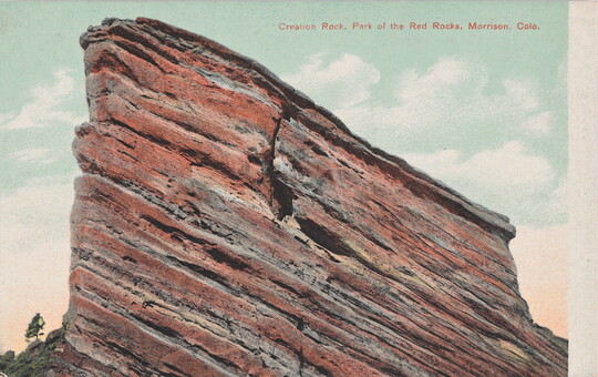 A color postcard of a tall, red rock formation jutting into the sky.