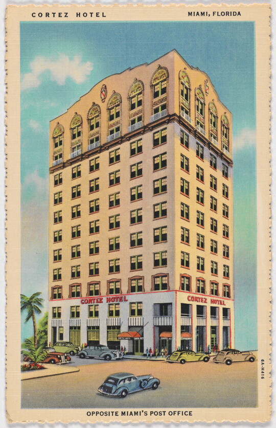 A color postcard of a multi-story hotel with many windows and cars parked in front.