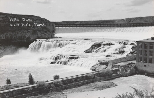 A black-and-white postcard of water flowing through a dam.