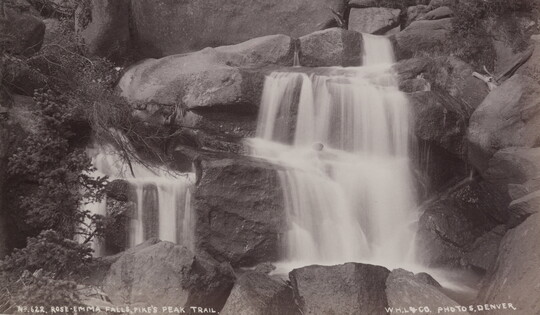 A black-and-white photograph of rushing water tumbling down rocks.