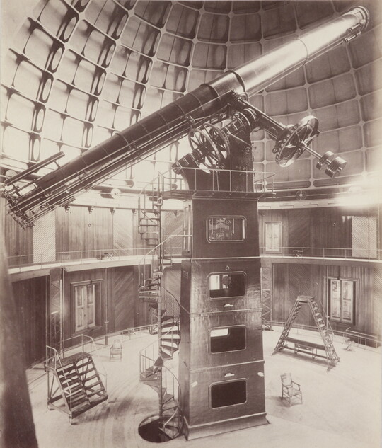 A sepia-toned photograph of a large telescope inside of a domed structure.