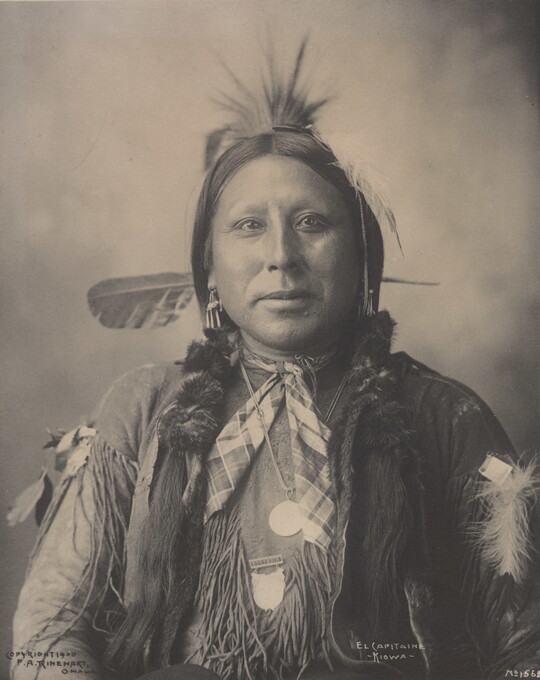 A black-and-white formal portrait of an Indigenous man in traditional clothing.