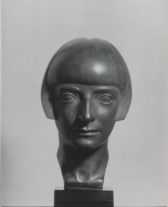 A black-and-white photograph of a bronze bust of a woman with a bobbed haircut from the front.