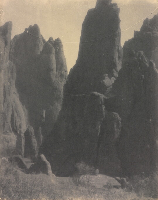 A black-and-white photograph of large hoodoos, or vertical spires of rock.
