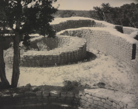 A sepia-toned photograph of open-topped brick structures forming round and curved enclosures.