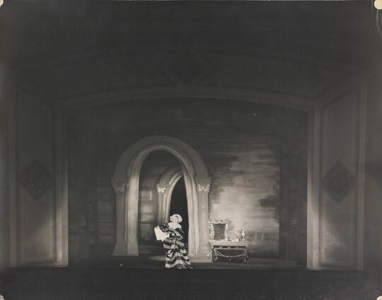 A black-and-white photograph of a woman performing on a stage.