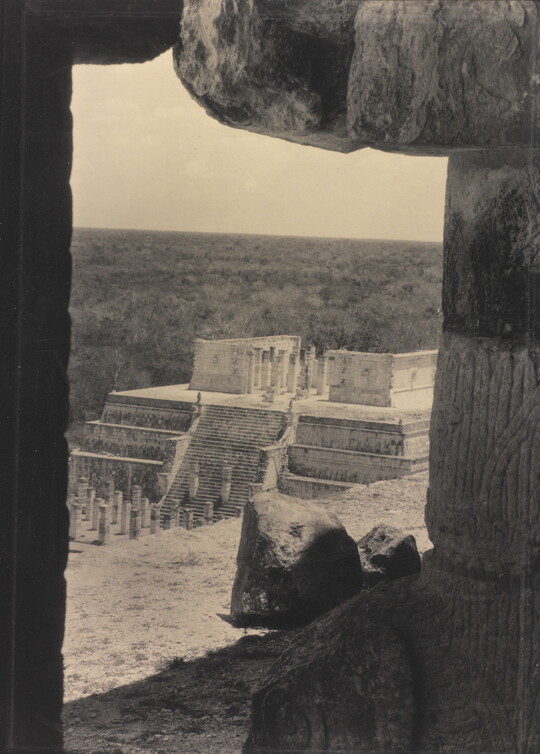 A sepia-toned photograph of an ancient step pyramid viewed through a stone window.