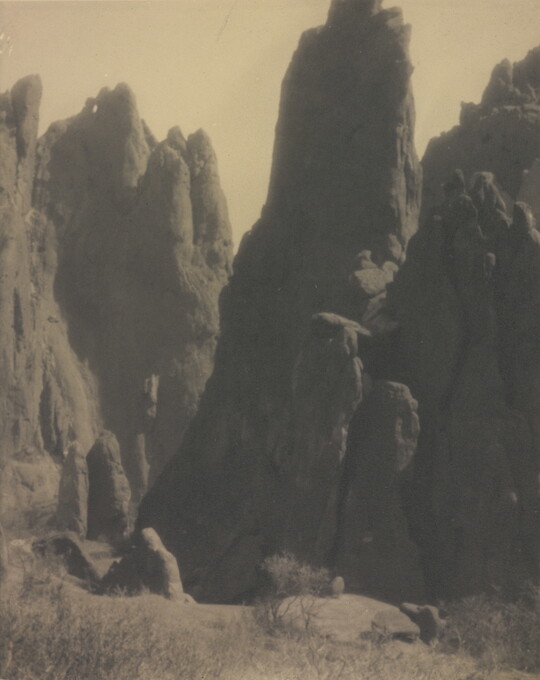 A black-and-white photograph of large hoodoos, or vertical spires of rock.