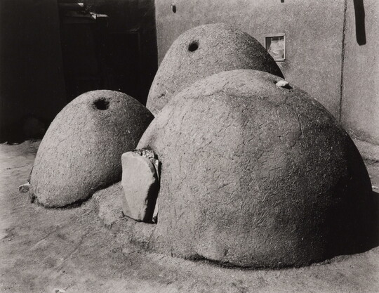 A black-and-white photograph of three large, round beehive ovens.