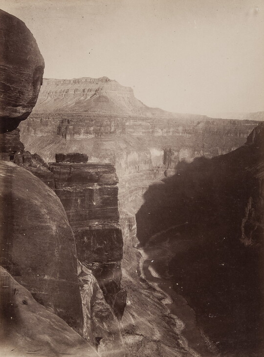 A black-and-white photograph, taken from high up, overlooking a winding river surrounded by cliffs.