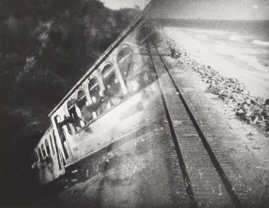 A black-and-white photograph of a train car overlayed with a photograph of train tracks.