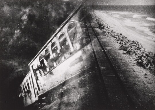 A black-and-white photograph of a train car overlayed with a photograph of train tracks.