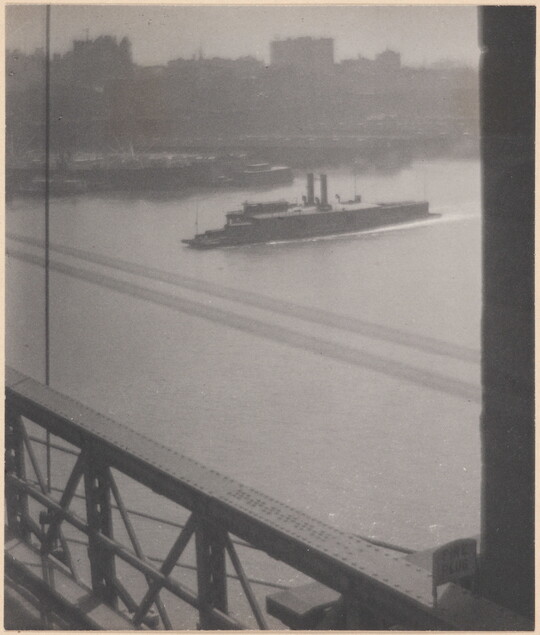 A black-and-white photograph of a boat preparing to cross under a bridge as viewed from the bridge.