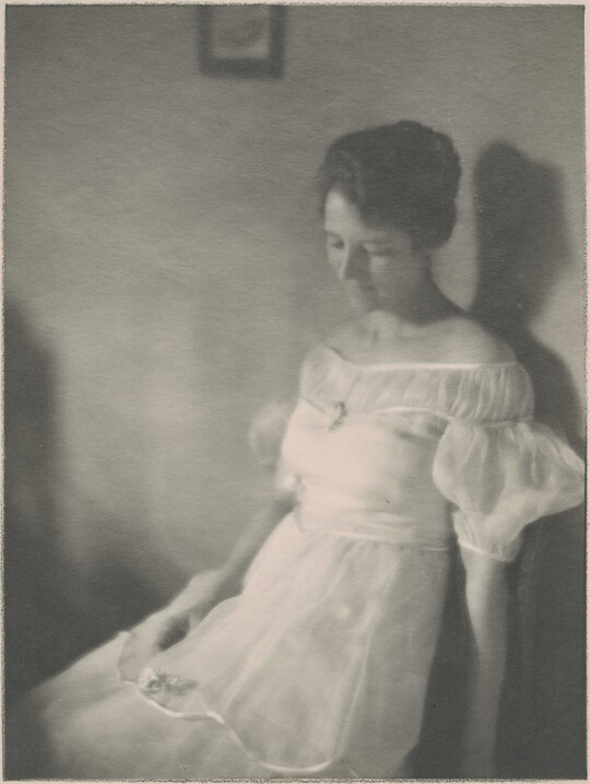 A black-and-white photograph of a seated White woman with dark hair in an up-do wearing a white ruffled dress.