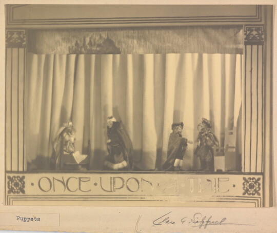 A sepia-toned photograph of a puppet stage with four puppets and the words "Once Upon a Time" written at the bottom.