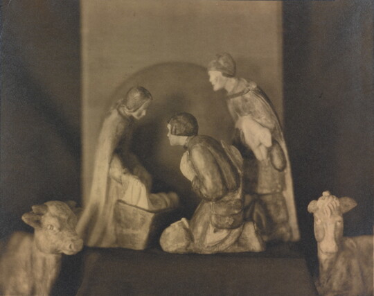 A sepia-toned photograph of human and animal figurines assembled in a nativity scene.