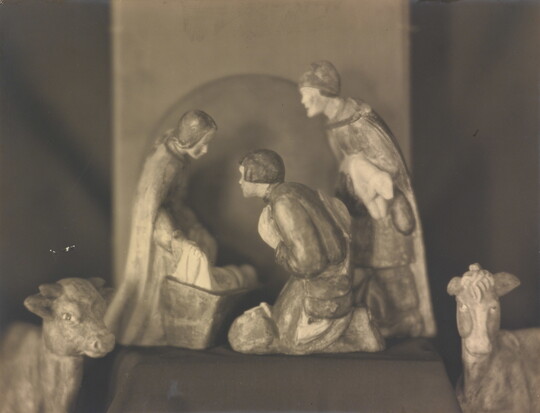 A sepia-toned photograph of human and animal figurines assembled in a nativity scene.