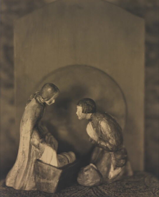 A sepia-toned photograph of human figurines assembled in a nativity scene.