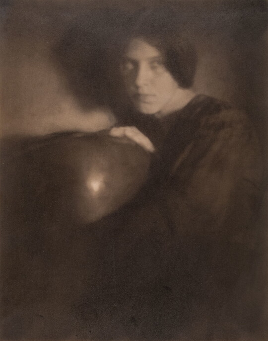A black-and-white photograph of a White woman in dark clothing holding a bowl.