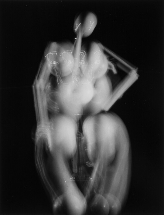 An abstract black-and-white photograph of what looks like an artist's mannequin that has been double-exposed to suggest movement.