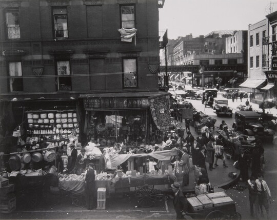 A black-and-white photograph of intersecting city streets crowded with people and vendors for a street market.
