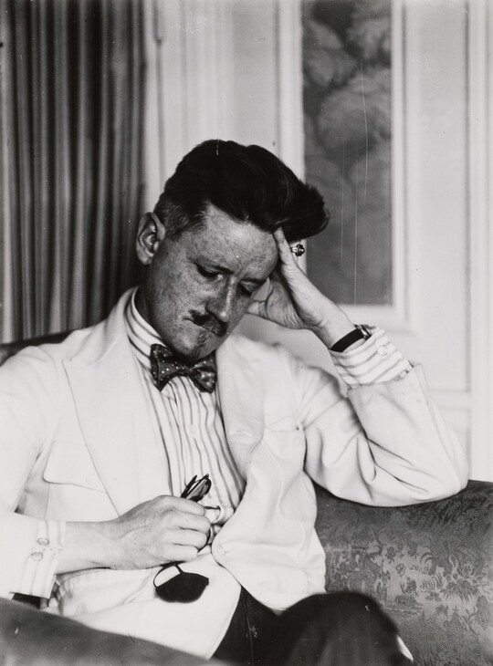 A black-and-white portrait photograph of a seated, nicely dressed White man resting his head on his hand.
