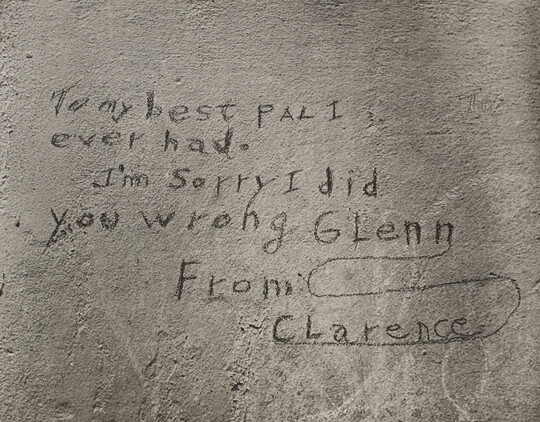 A black-and-white photograph of a note written on what looks like a cement wall that reads: "To my best pal I ever had. I'm sorry I did you wrong Glenn. From Clarence."