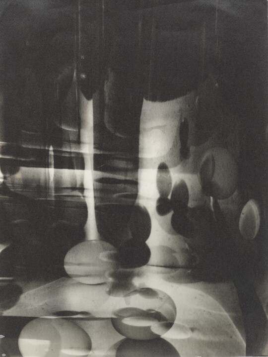 A black-and-white photograph of abstracted egg shapes layered and reflected on top of one another.