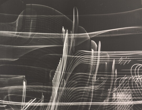 A black-and-white photograph of abstract streaks of white light swirling horizontally and vertically on a black background.