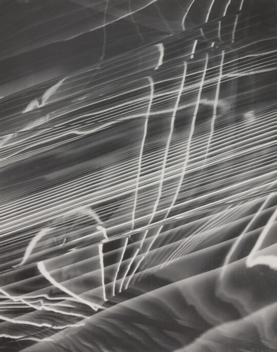 A black-and-white photograph of abstract white lines radiating horizontally, layered on top of a rippled background.