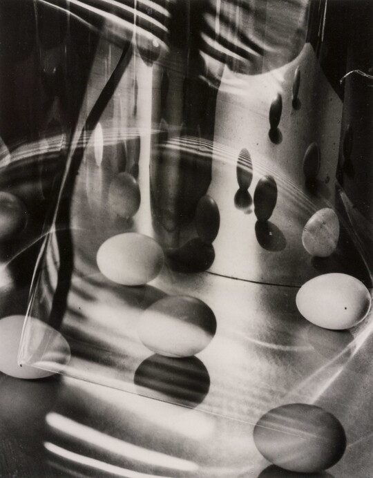 A black-and-white abstract photograph of eggs and light reflected in glass and mirrors.