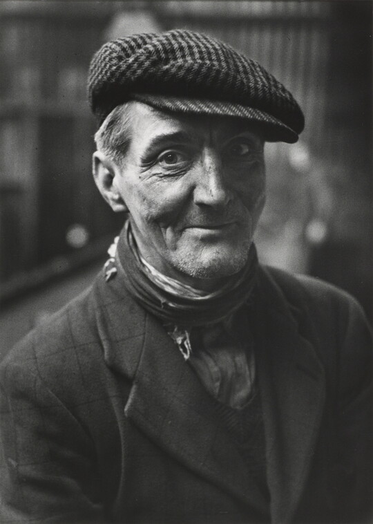 A black-and-white portrait photograph of a smiling man looking at the camera.
