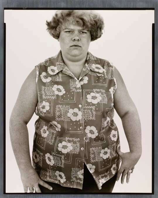 A black-and-white portrait photograph of a White woman with short hair in a sleeveless button-down shirt with a floral pattern.