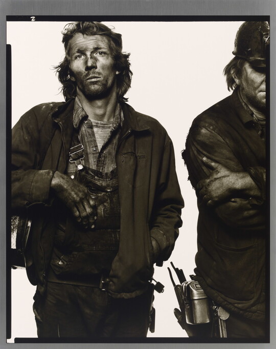 A black-and-white portrait photograph of two men, the one on the right is only half in the frame, in dirty work clothes covered in dark coal dust.