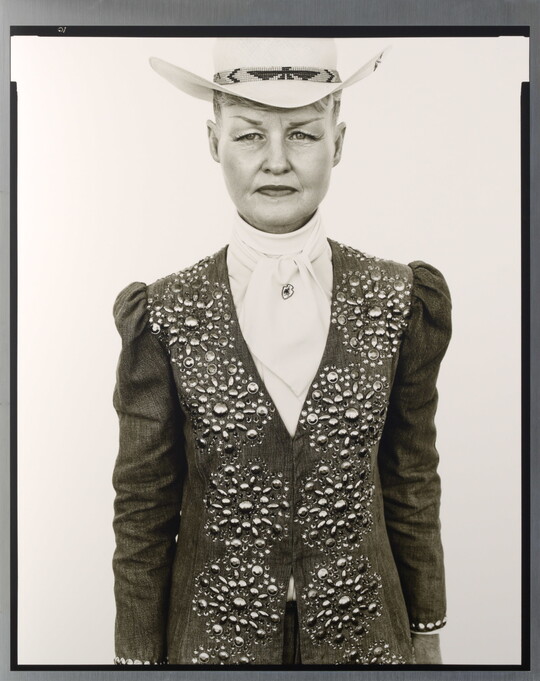A black-and-white portrait photograph of a White woman wearing a white cowboy hat and a jacket embellished with rhinestones in a floral pattern over a white blouse.