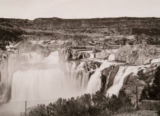 A black-and-white photograph of waterfalls tumbling down a rock face.