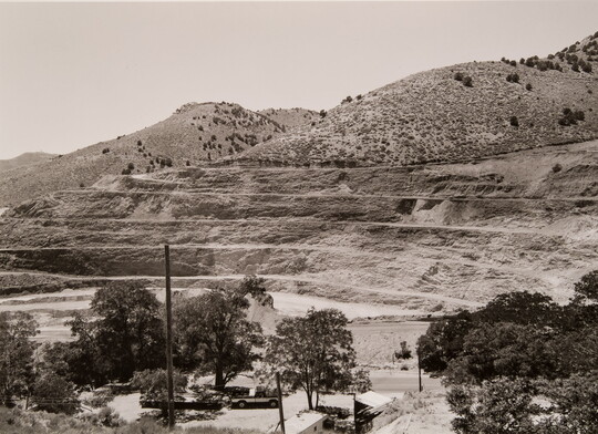 A black-and-white photograph of a mountainside that has been strip mined and the town below.