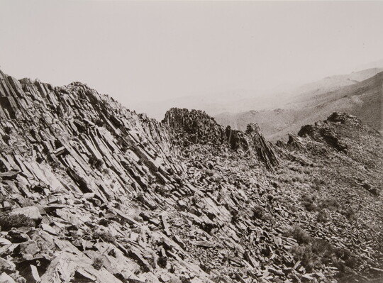 A black-and-white photograph of a rocky mountain ridge.