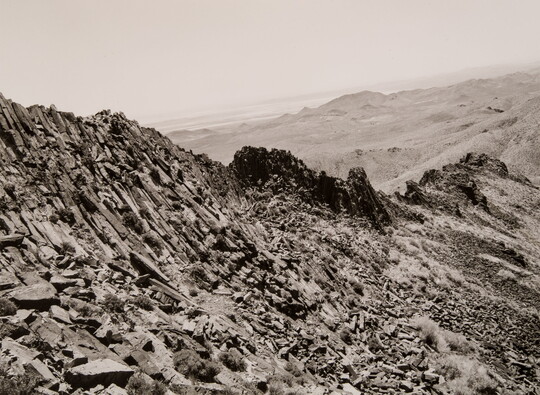 A black-and-white photograph of a rocky mountain ridge.