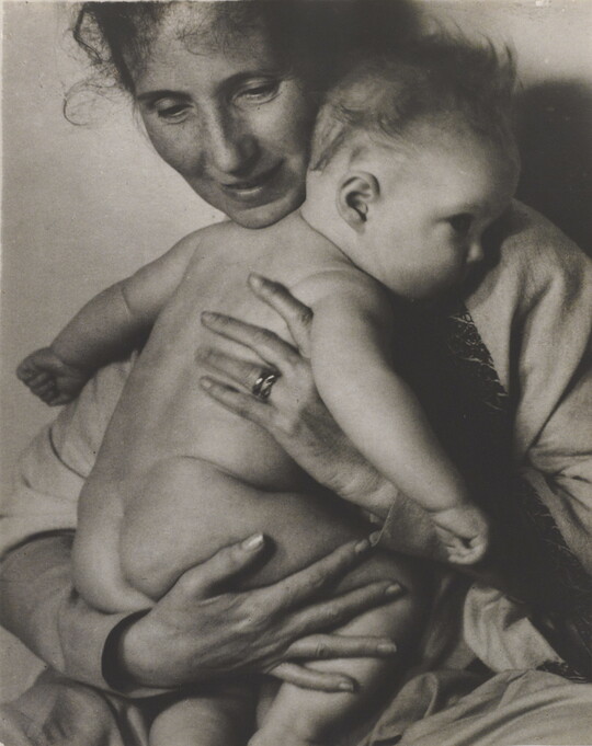 A black-and-white photograph of a White woman holding a naked baby to her chest.