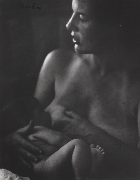 A black-and-white photograph of a White woman nursing a naked infant.