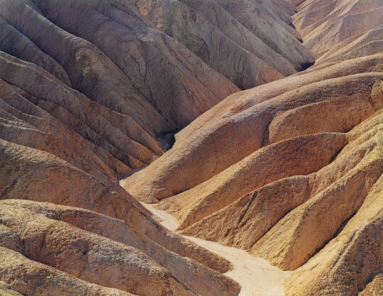 A color photograph of a desert valley between two arid mountains.
