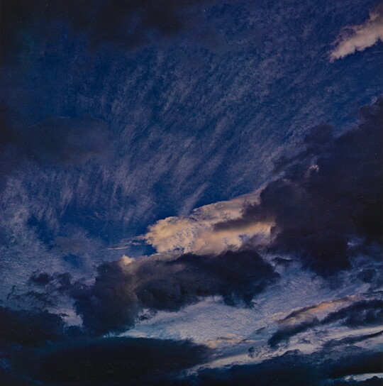 A color photograph of a dark blue sky streaked with clouds.