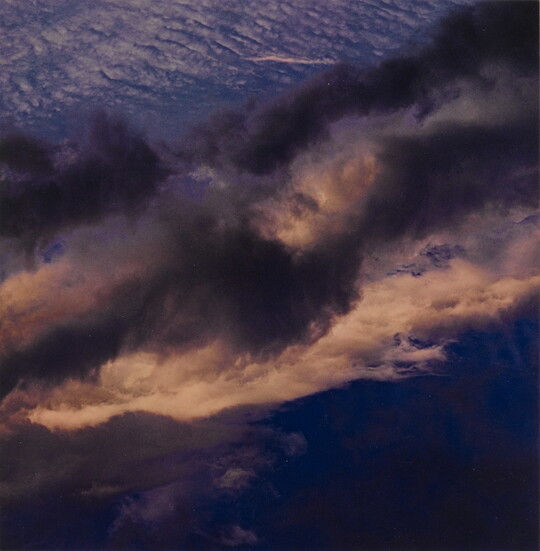 A color photograph of a dark blue sky streaked with dark and light clouds.