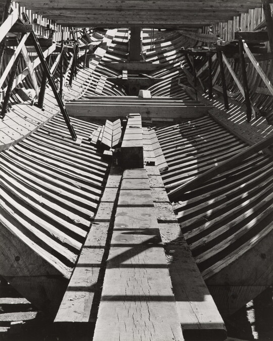 A black-and-white photograph of the inside wood frame of an unfinished ship.