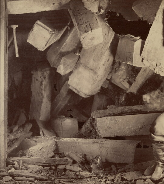 A sepia-toned photograph of fallen wood and debris blocking what was previously the opening of a mine.