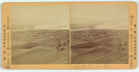 Two almost identical side-by-side sepia-toned photographs of flat land dotted with buildings next to a body of water.